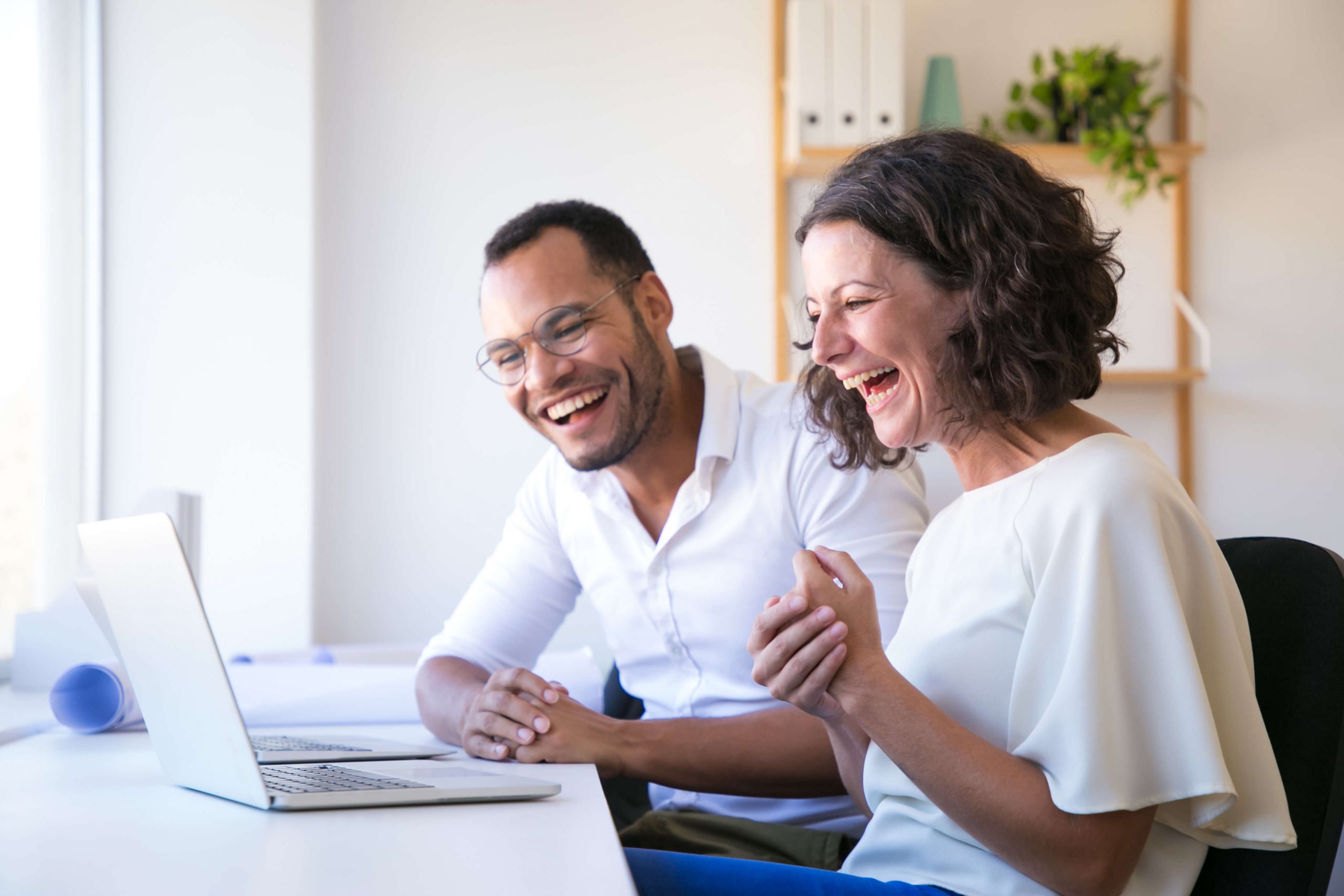 cheerful employees looking laptop laughing